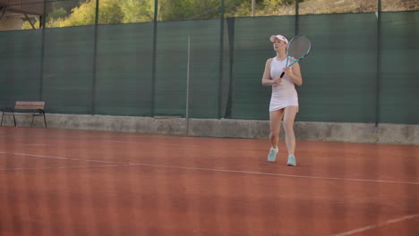 close-up of woman holding tennis racket in both hands to straighten strike. close-up of young attractive woman playing tennis at tennis court. player holding outfit. slow motion