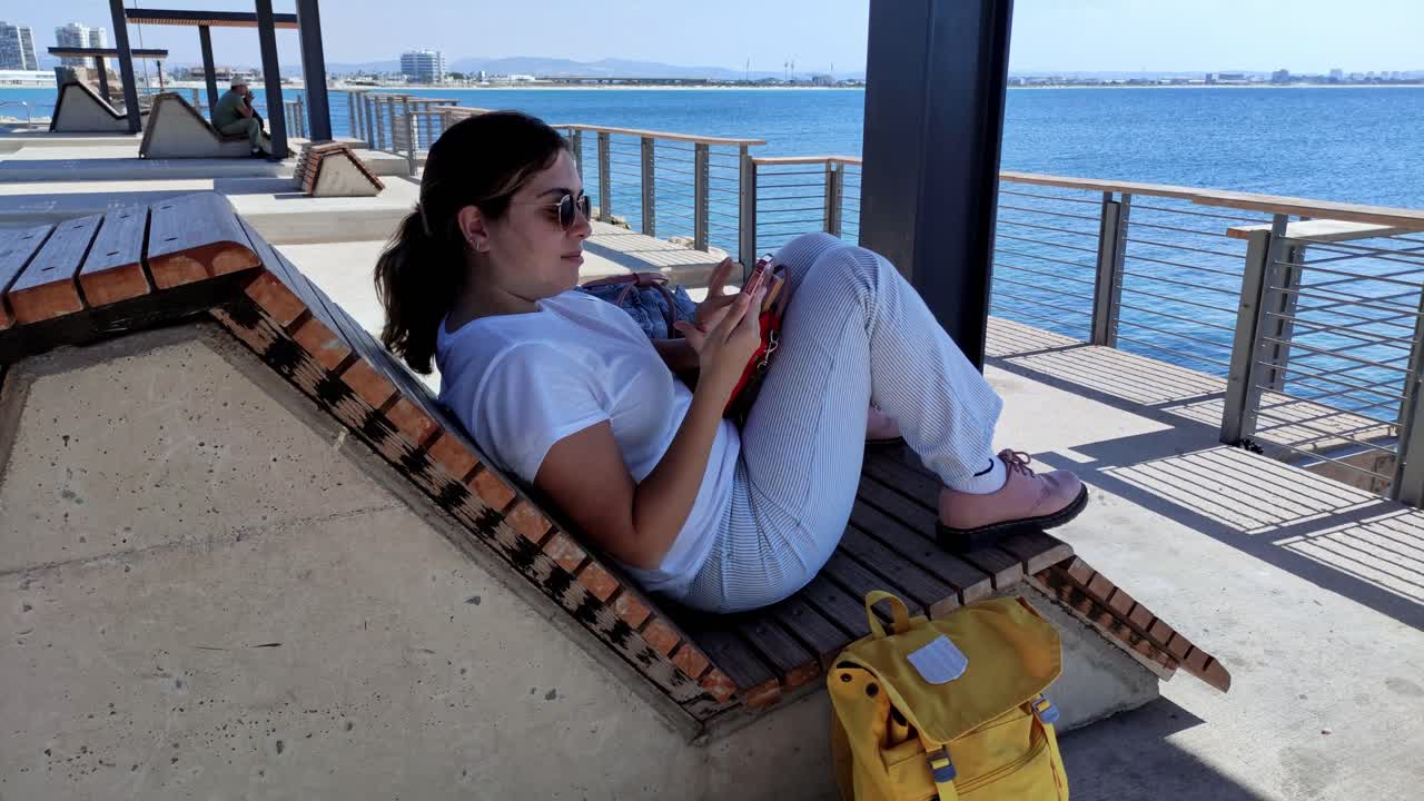Donna che si rilassa su una panchina del lungomare con vista sul mare di Acri