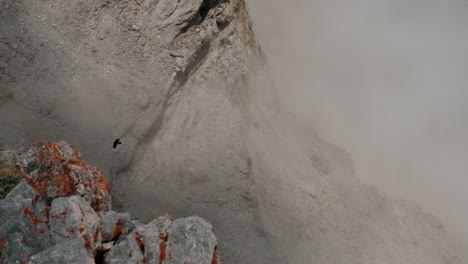 Un-Cuervo-Volando-A-Gran-Altura-A-Través-De-Las-Montañas-Rocosas-En-Un-Día-De-Niebla---Tiro-Lento-De-ángulo-Alto