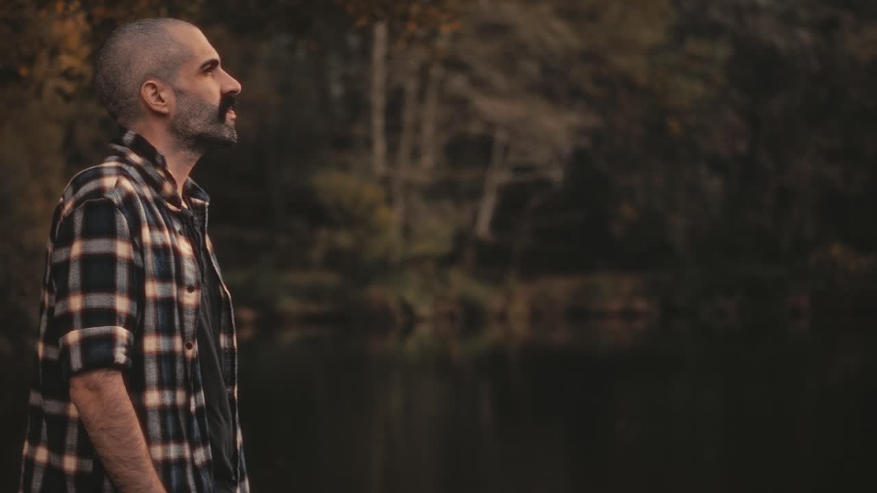 Young man by river or lake in Portugal loves nature. Golden sunlight creates warm mood. Perfect clip for nature, travel, or self-development