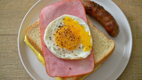 homemade bread toasted cheese topped ham and fried egg with pork sausage for breakfast