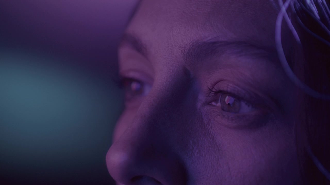 Primo piano estremo degli occhi di una donna illuminati da luci neon multicolori