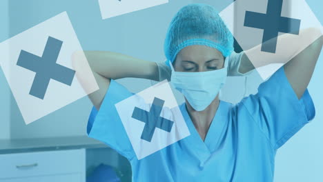 animation of black crosses on white squares over masked female surgeon in operating theatre