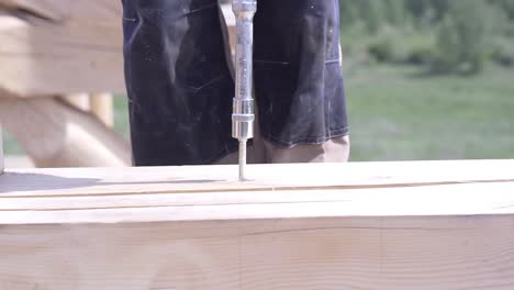 construcción de casas de troncos: instalación de tornillos en vigas de madera