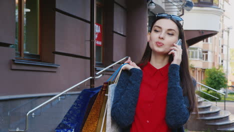 stylish brunette with shopping bags walking on the city talking on the phone hd video