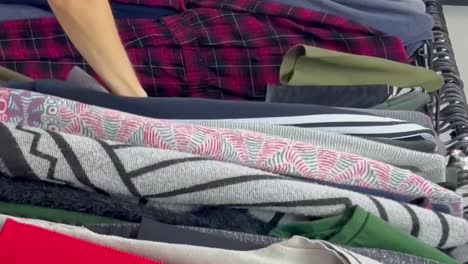 rows of secondhand clothes hang on hangers a woman buys used clothes rows of secondhand clothes hang on hangers a woman buys used clothes