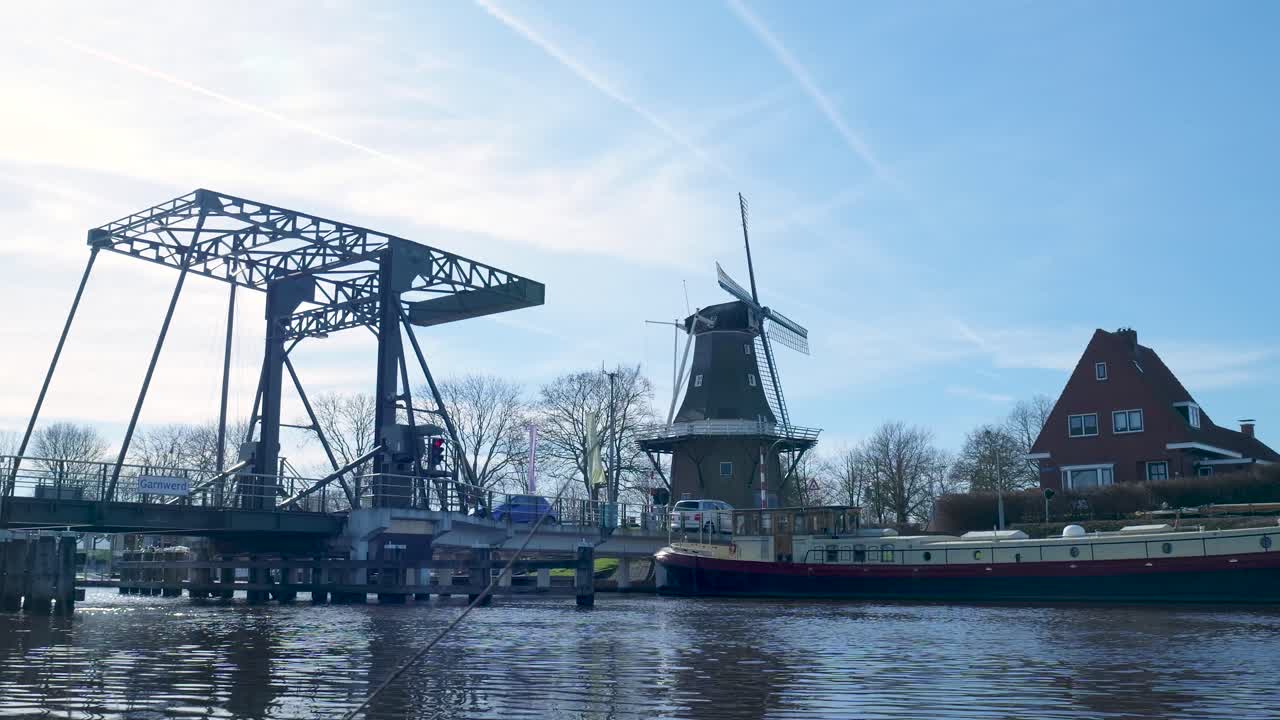 Ophaalbrug opent voor een boot op een kanaal met een windmolen.