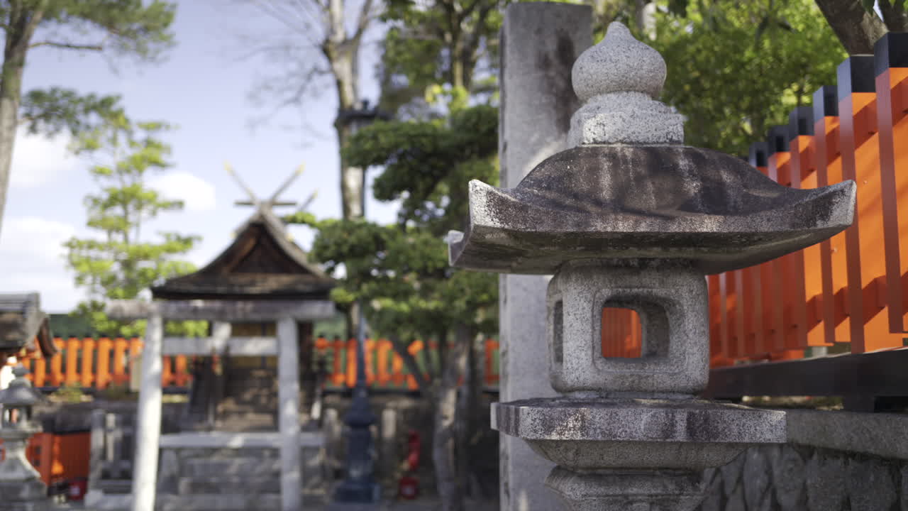 Wander through a stunning Japanese garden featuring intricately designed stone lanterns and bright red gates under a clear blue sky. Enjoy the peaceful ambiance. Kyoto, Fushimi-inari
