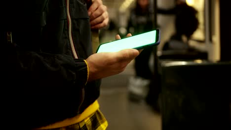 hombre de cerca usando un teléfono inteligente con pantalla verde en el tren