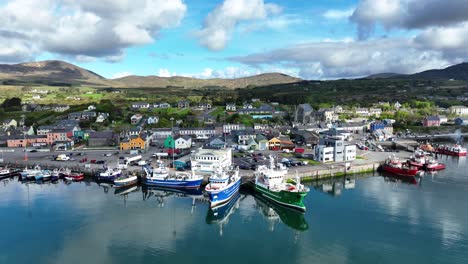 Drone-West-Cork-Castletownbere-Puerto-Pesquero-Con-Una-Concurrida-Ciudad-Comercial-Y-Montaña-En-El-Fondo,-Uno-De-Los-Puertos-Pesqueros-Más-Importantes-De-Irlanda-En-Un-Brillante-Día-De-Mayo