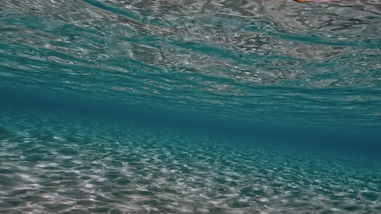 auténtica escena submarina de agua de mar tropical turquesa cristalina con superficie ondulada y reflejos en el fondo marino con fondo azul