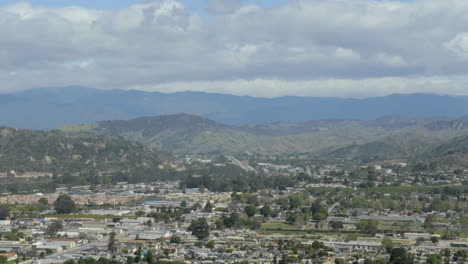 Un-Manto-Blanco-De-Nubes-Se-Eleva-Sobre-Una-Ciudad-En-Un-Gran-Valle