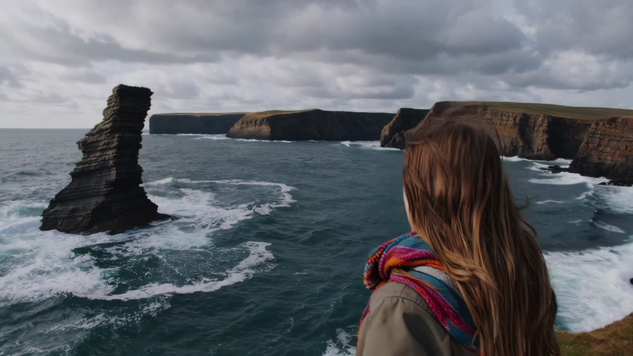 Woman admiring the dramatic coastal landscape with a sea stack