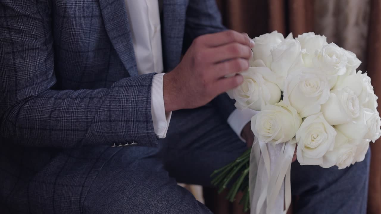 집에서 손에 웨딩 부켓을 들고 있는 신랑.  셔츠, 재