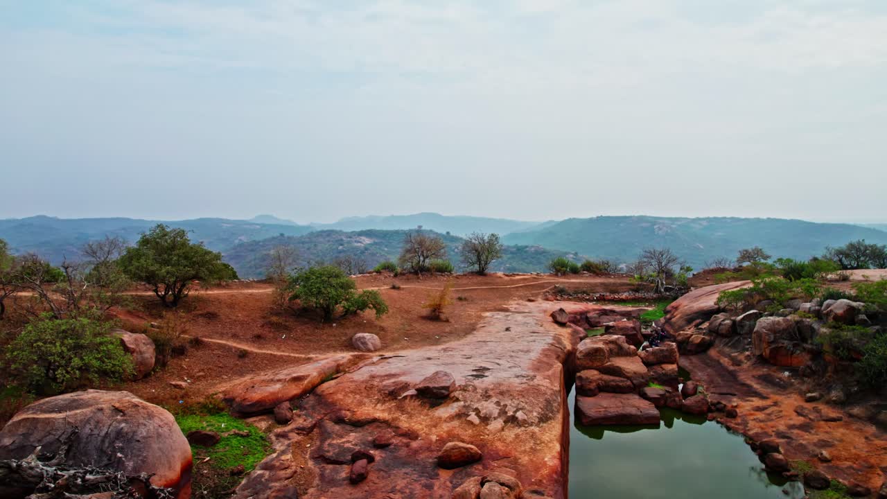 Reval shot of hill mountains with crop field lands from from dead red wood tree at rachakonda fort, hyderabad, telangana, india. day time, push in, drone shot, 4k.