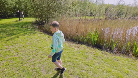 young boy walking down a grassy path surrounded by reeds and woodlands