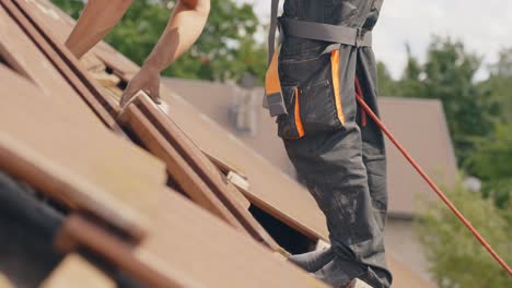 roofing scene of worker on rooftop removing tiles