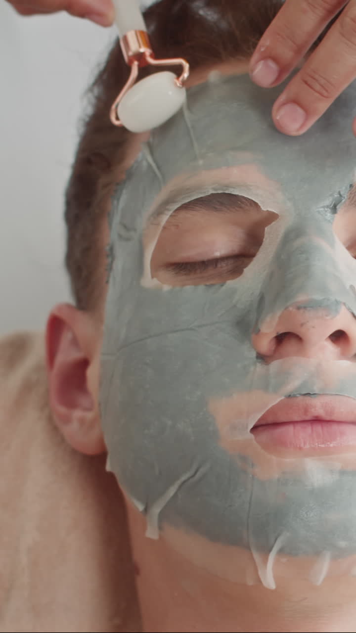 Man Getting Facial Treatment with Jade Roller and Masks at Beauty Studio