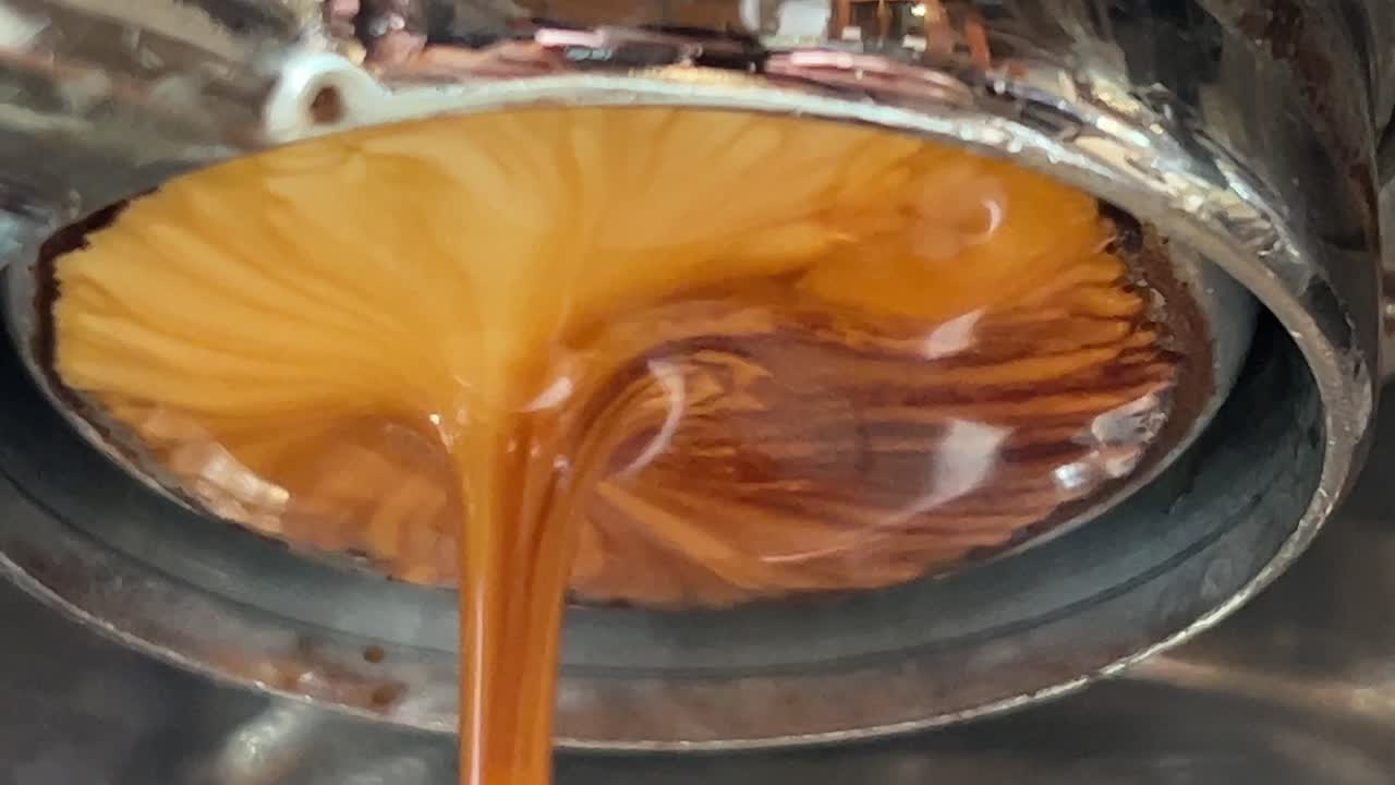 Single origin coffee espresso extraction from coffee machine basket, close up shot