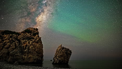 el lapso de tiempo cinematográfico de la vía láctea y las estructuras verdes, así como muchas estrellas en el cielo con rocas en primer plano