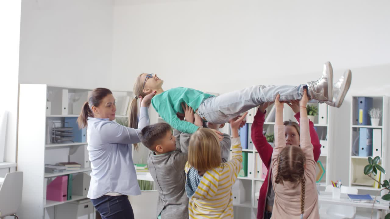 Kids Lifting Girl Up in Air during Relationship Building Workshop