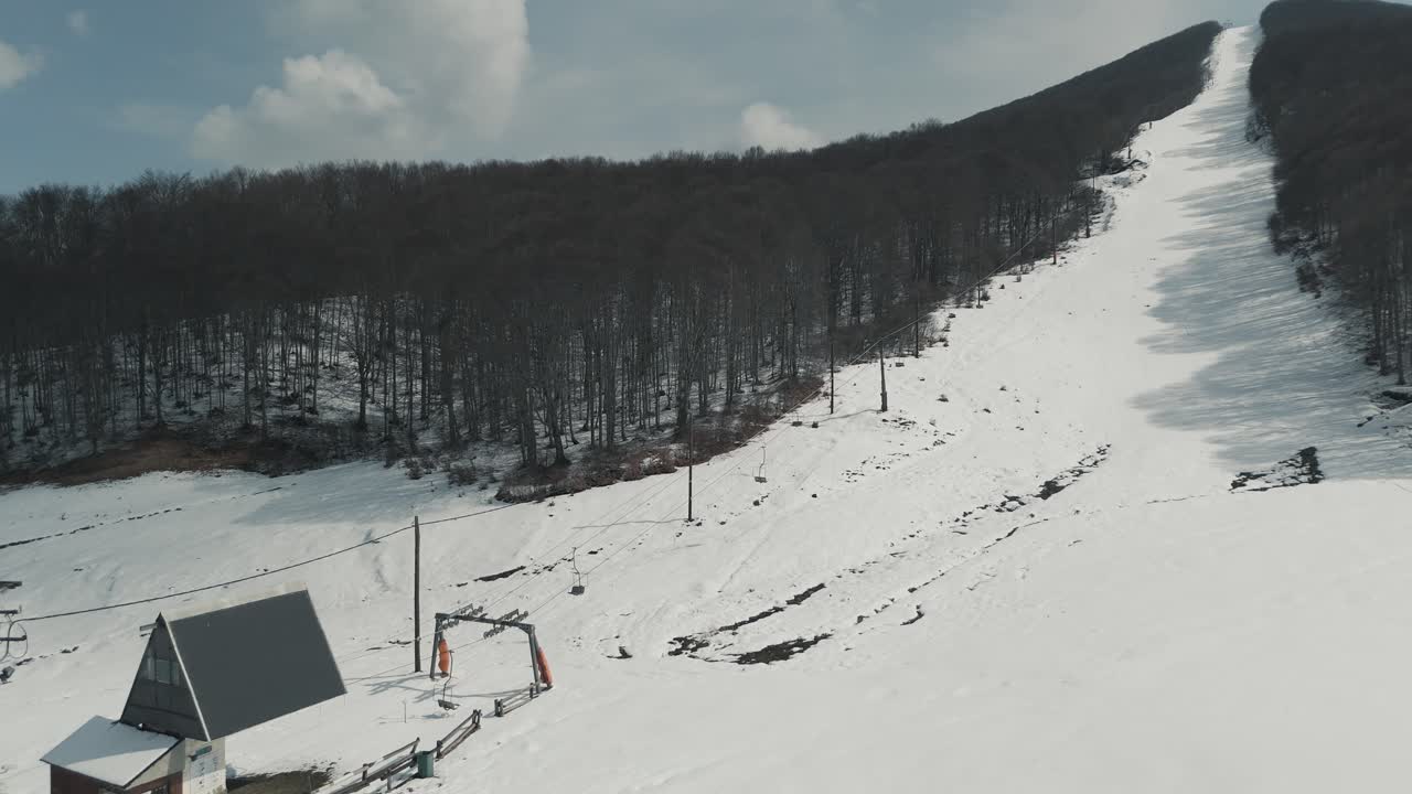 Ripresa con drone di montagna boscosa con neve, clima mite, mentre si vola sopra la pista da snowboard, video 4K, natura invernale europea