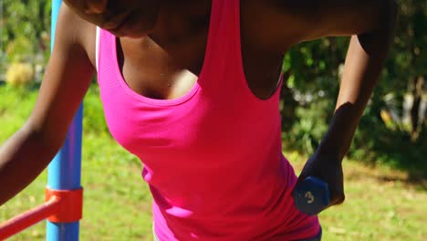 Female-athlete-exercising-with-dumbbell-in-the-park-4k