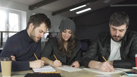 Equipo-De-Jóvenes-Profesionales-Que-Se-Reúnen-En-Una-Oficina-Creativa.-Tomando-Notas-Y-Haciendo-Una-Lluvia-De-Ideas.-Discusión-De-Negocios.-Tazas-De-Café-Sobre-La-Mesa.-Filmado-En-4k