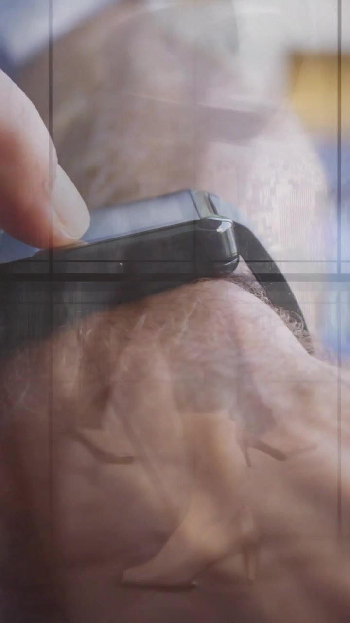 Vertical video: Man raising wrist and swiping watch through glass, green UI showing tech data