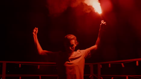 hombre agresivo quemando bengala de señal en el techo. fanático de fútbol de pie con fuego