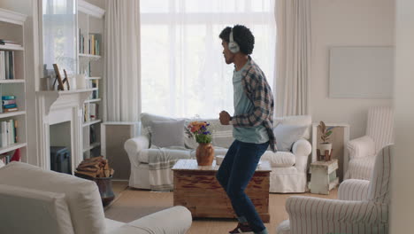 happy young man dancing at home celebrating success listening to music wearing headphones having fun dance in living room on weekend