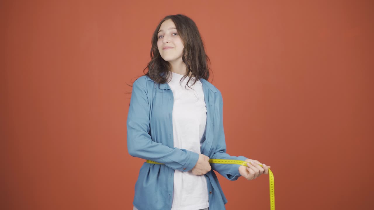 자신의 몸무게에 만족하는 젊은 여성.