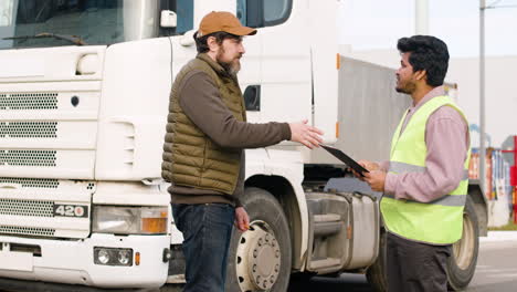 capo e lavoratore che organizzano una flotta di camion in un parco logistico 1