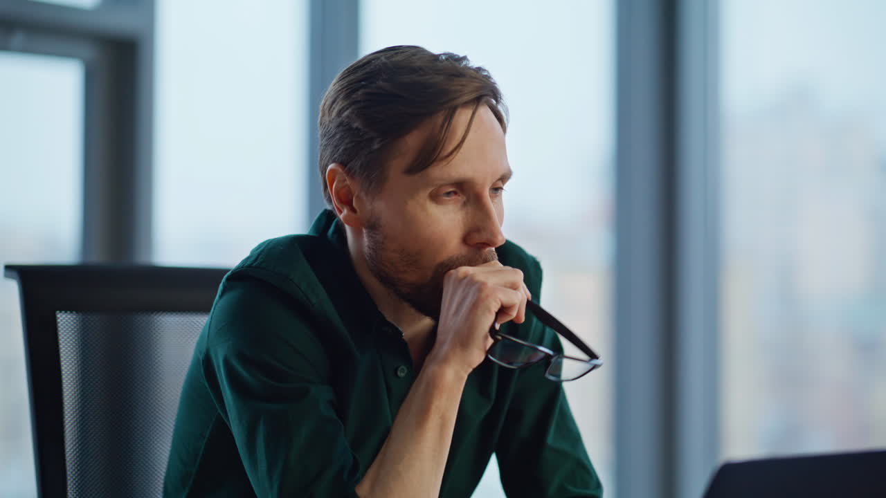 Pensive startuper thinking project taking off glasses at workplace closeup