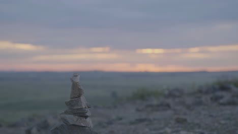 sunrise over a grassy valley with a stone cairn