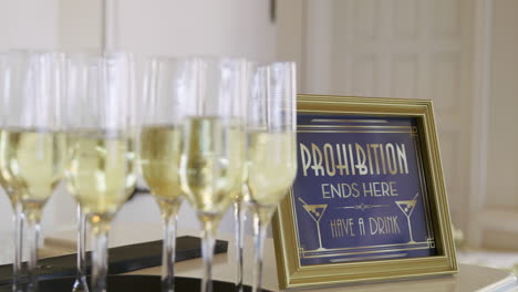 sparkling wedding champagne glasses in front of sign that says have a drink