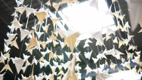 paper cranes hanging from a ceiling with a skylight