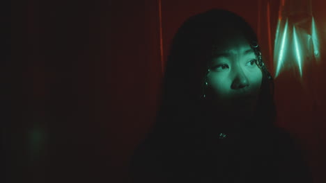 beautiful asian woman standing among plastic wrap curtains in neon light