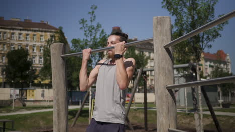 a man doing a slow motion pull up during a workout in a park