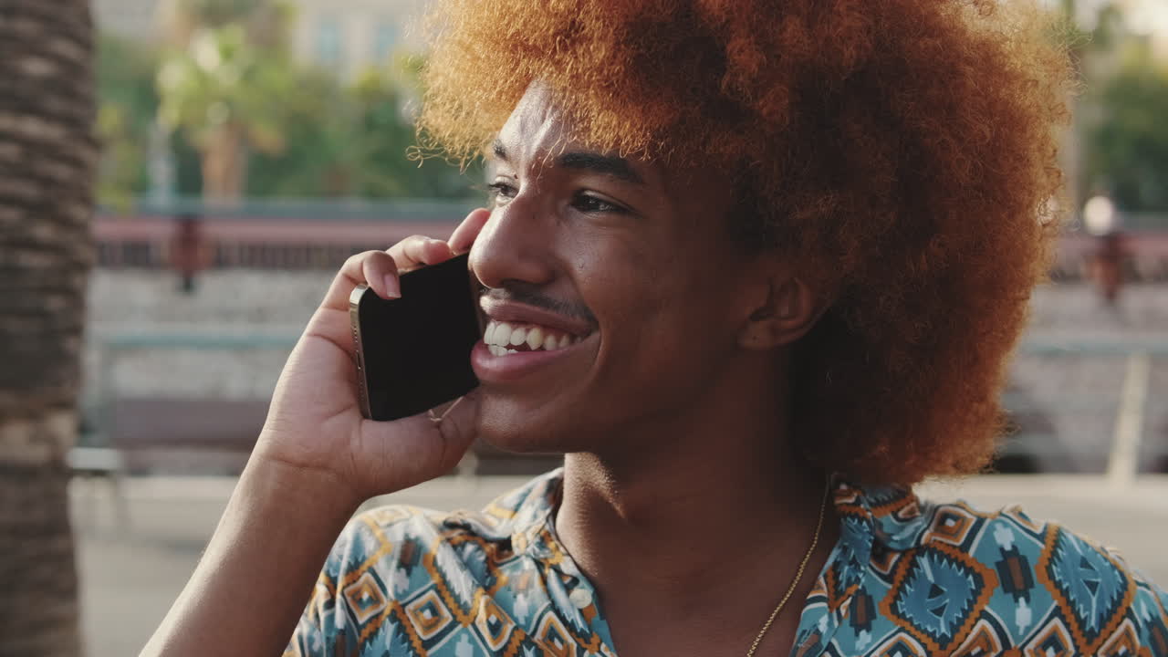Young Man with Curly Red Hair Talking on Smartphone and Laughing