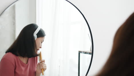 woman singing and brushing hair in front of mirror