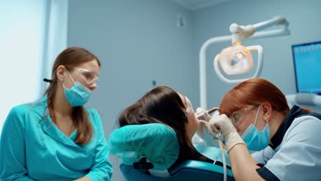 female client receiving treatment for cavities. dental specialist treats woman's teeth with dental machine in modern stomatology office.