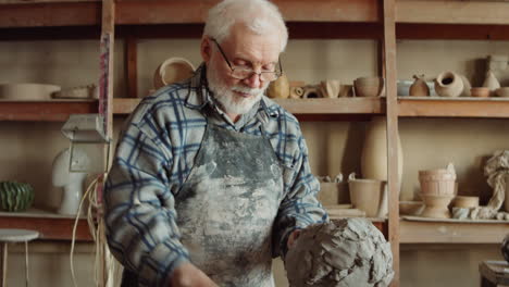 senior sculptor modeling clay head with tool