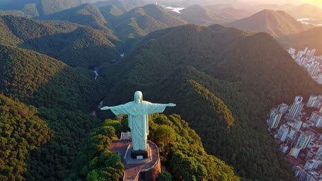 aerial video captures a majestic statue atop a lush mountain, with a panoramic view of surrounding