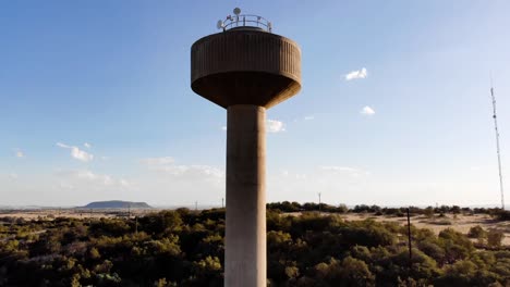 drone reveal shot of a broadcast tower in a rural area on a sunny day