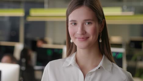 portrait of beautiful young woman wearing white shirt looking up to the camera and smiling charmingly. successful female working in open space office