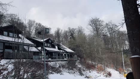 Holzhaus-Auf-Weißem-Hügel-Mit-Schnee-Und-Baum-Im-Vordergrund-In-Winterlicher-Winterlandschaft