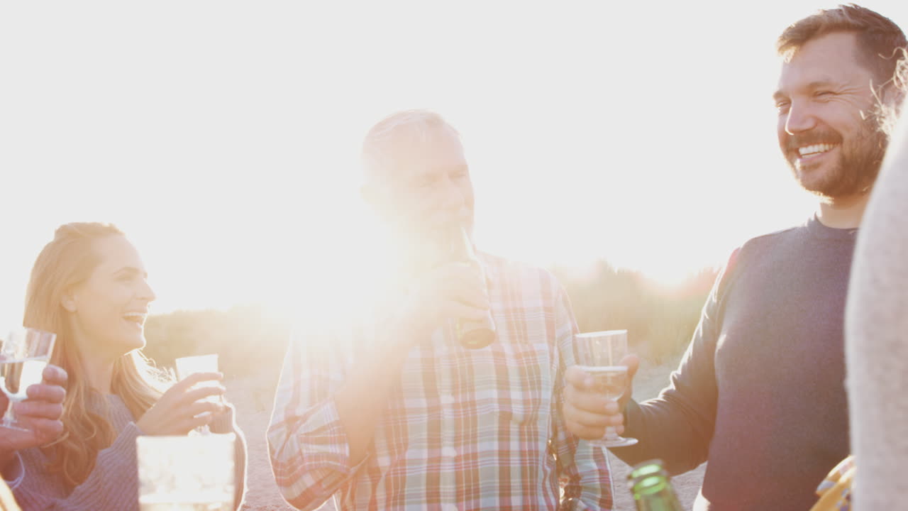 다세대 성인 가족이 겨울 해변 휴가에서 알코올과 함께 토스트를 하고 있습니다.