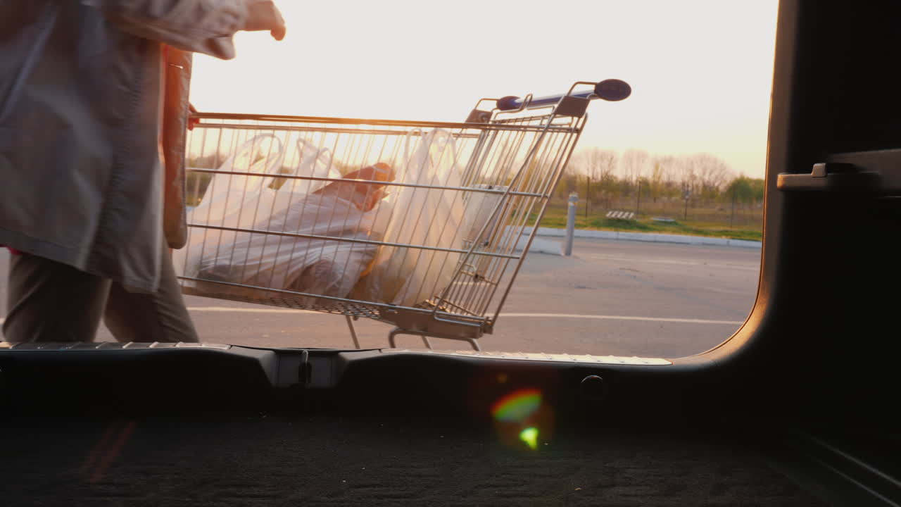 여자는 쇼핑백을 차 트렁크에 넣는다