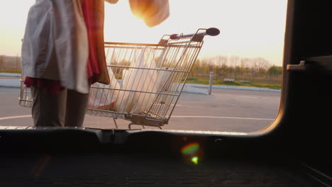 mujer pone bolsas de compras en el maletero de un coche